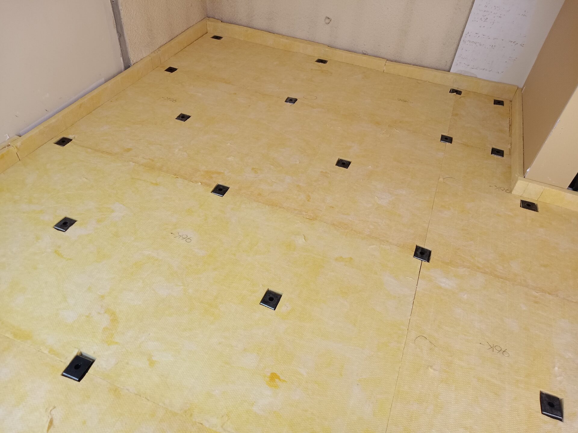 解体後の床にグラスウールと防振ゴムを施工する様子