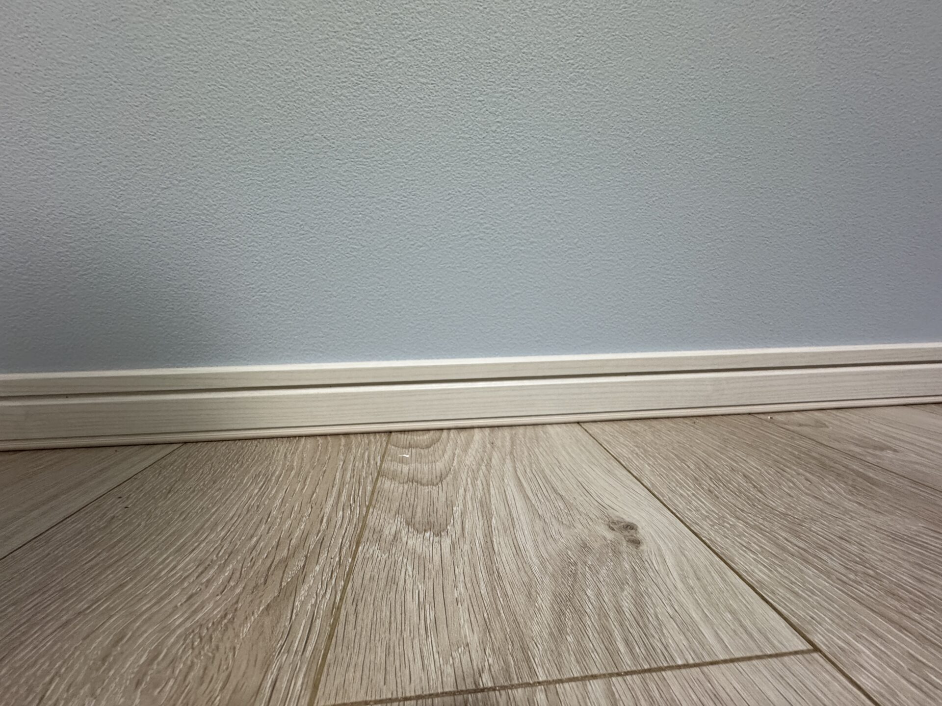 パステルブルーに白い巾木、オーク柄の合板フローリング